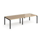 Four back-to-back desks with wood-effect tops and black metal frame on a white background