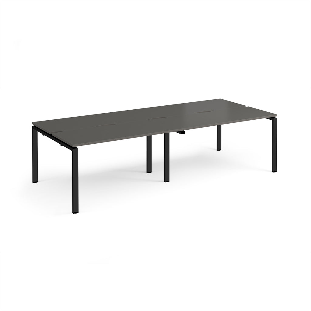 Four back-to-back desks with grey tops and black metal frame on a white background