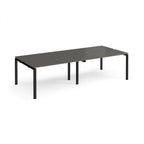 Four back-to-back desks with grey tops and black metal frame on a white background