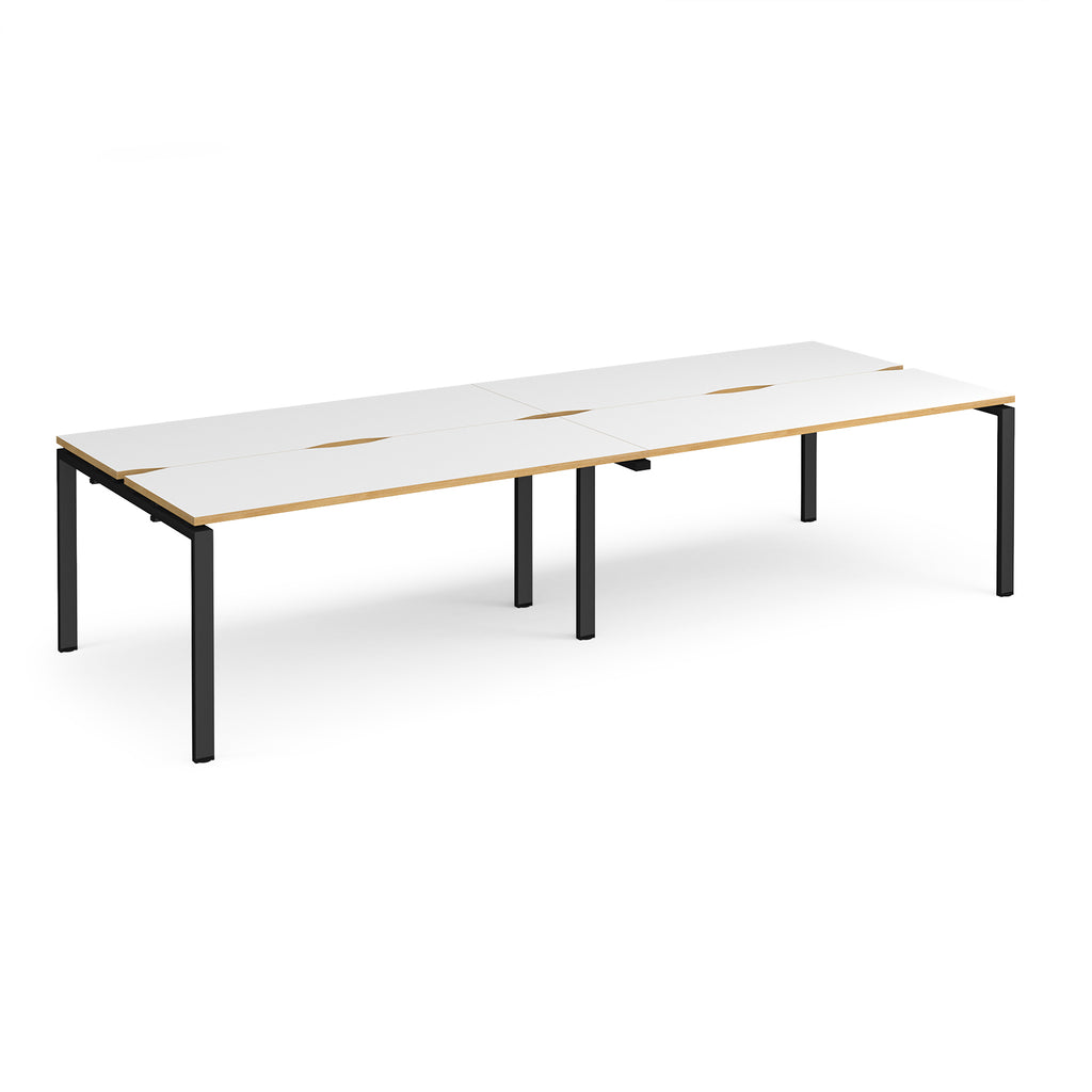 Four back-to-back desks with white tops with wooden edges and black metal frame on a white background