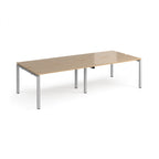 Four back-to-back desks with wood-effect tops and silver metal frame on a white background