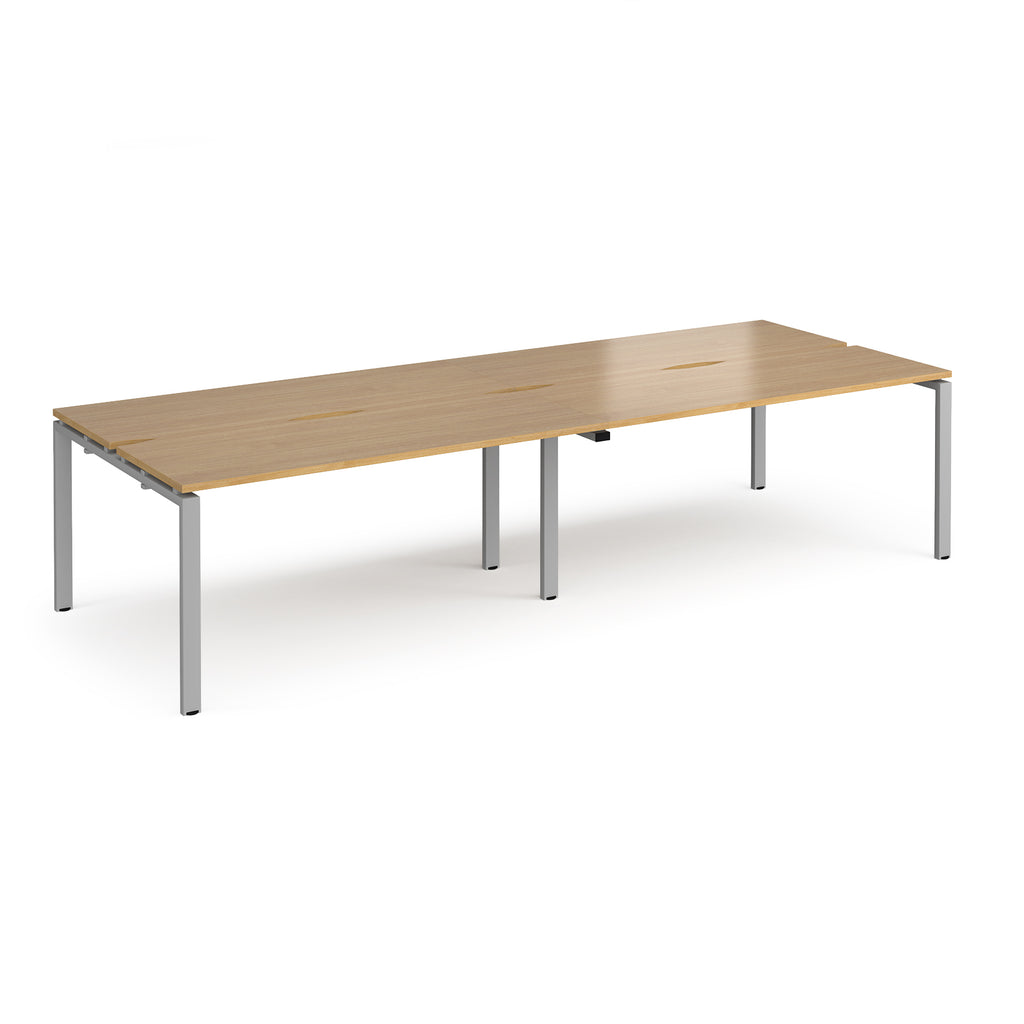 Four back-to-back desks with wood-effect tops and silver metal frame on a white background