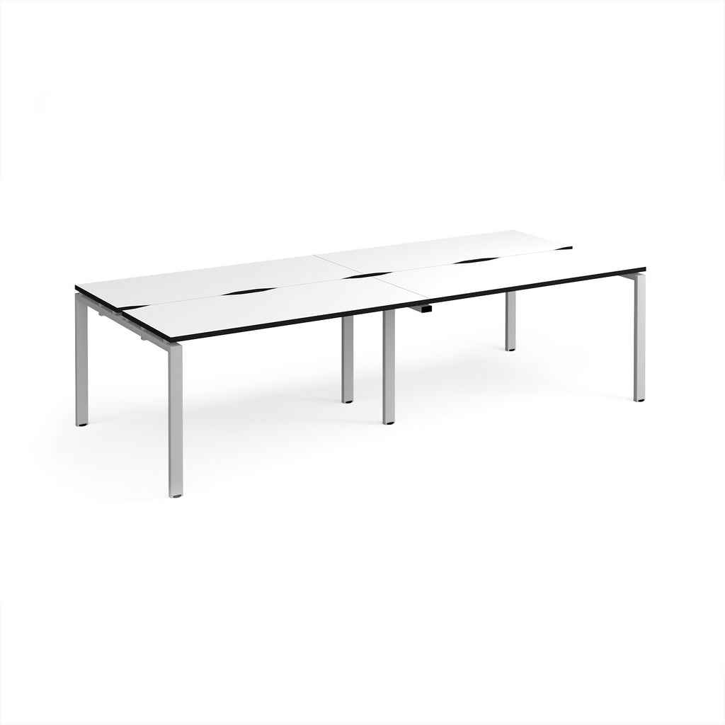 Four back-to-back desks with white tops with black edges and silver  metal frame on a white background