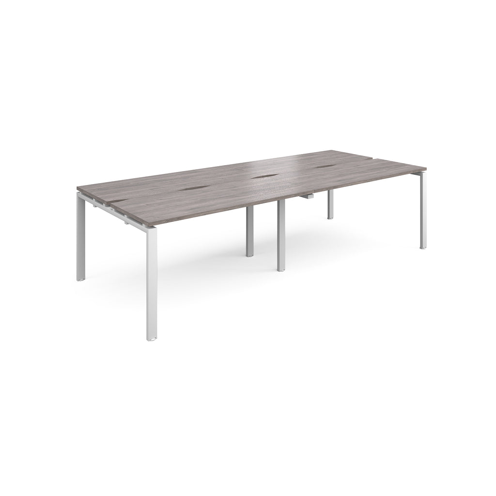 Four back-to-back desks with grey wood-effect tops and white metal frame on a white background
