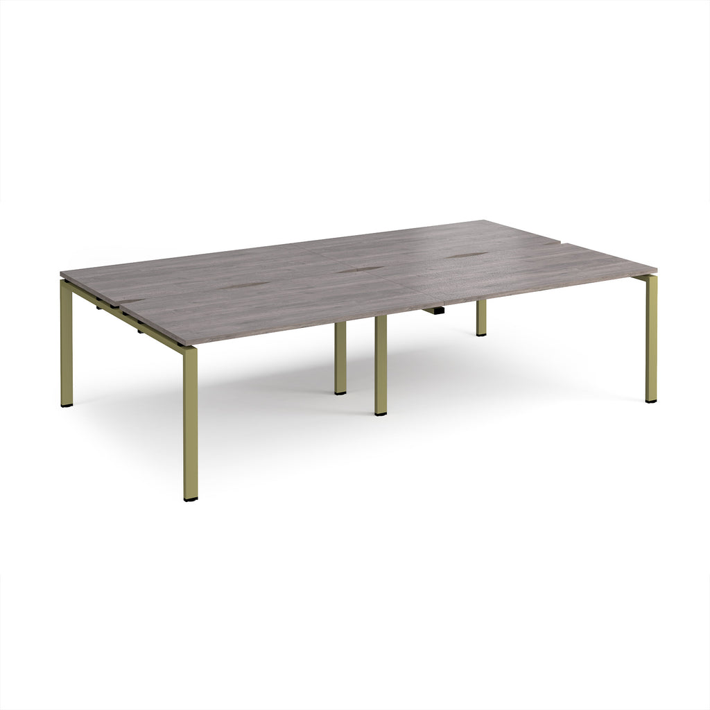 Four back-to-back desks with grey wood-effect tops and green metal frame on a white background