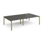 Four back-to-back desks with grey tops and green metal frame on a white background