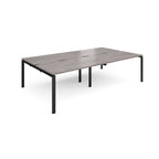 Four back-to-back desks with grey wood-effect tops and black metal frame on a white background