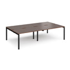 Four back-to-back desks with wood-effect tops and black metal frame on a white background