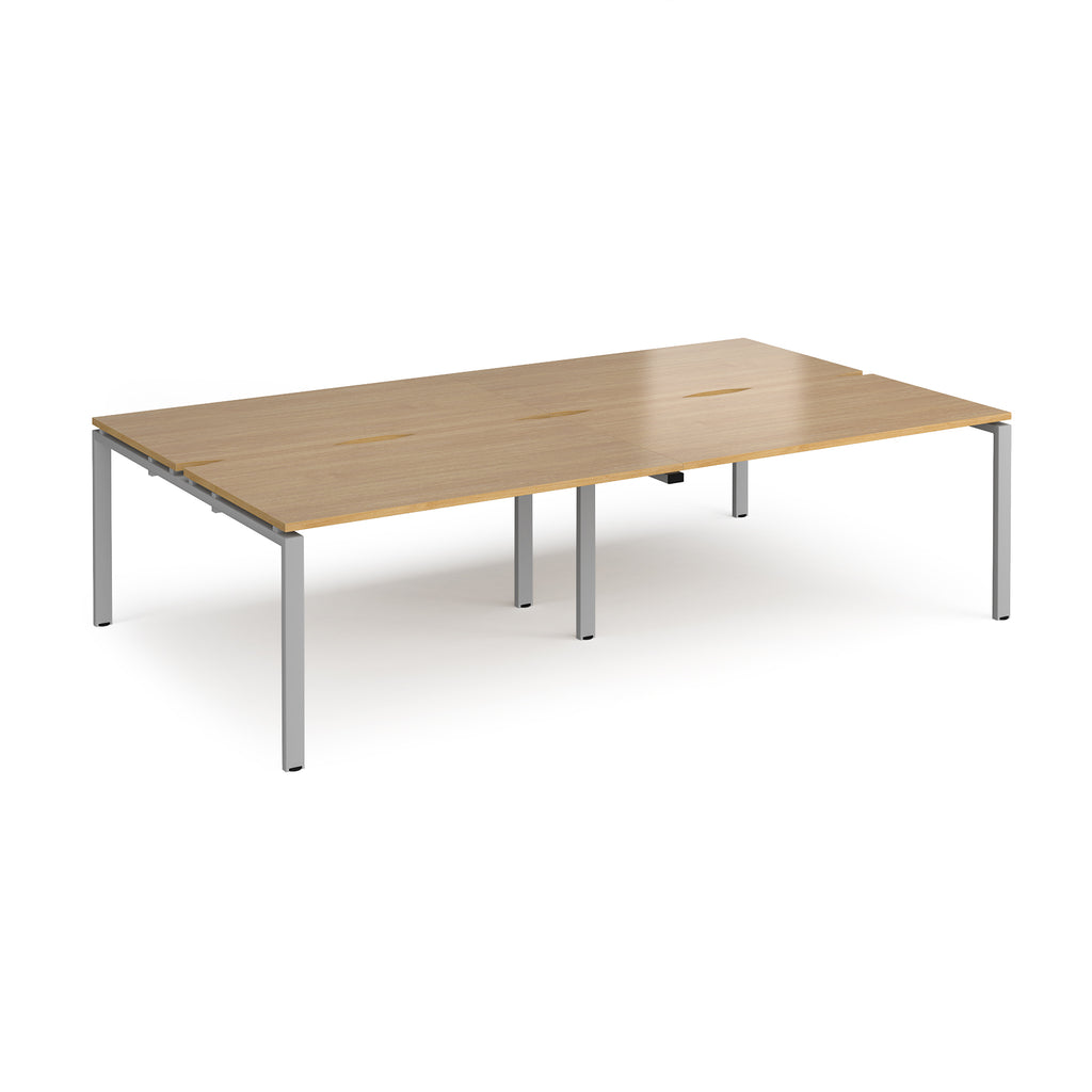Four back-to-back desks with wood-effect tops and silver metal frame on a white background
