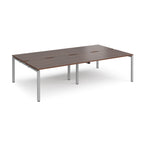 Four back-to-back desks with wood-effect tops and silver metal frame on a white background