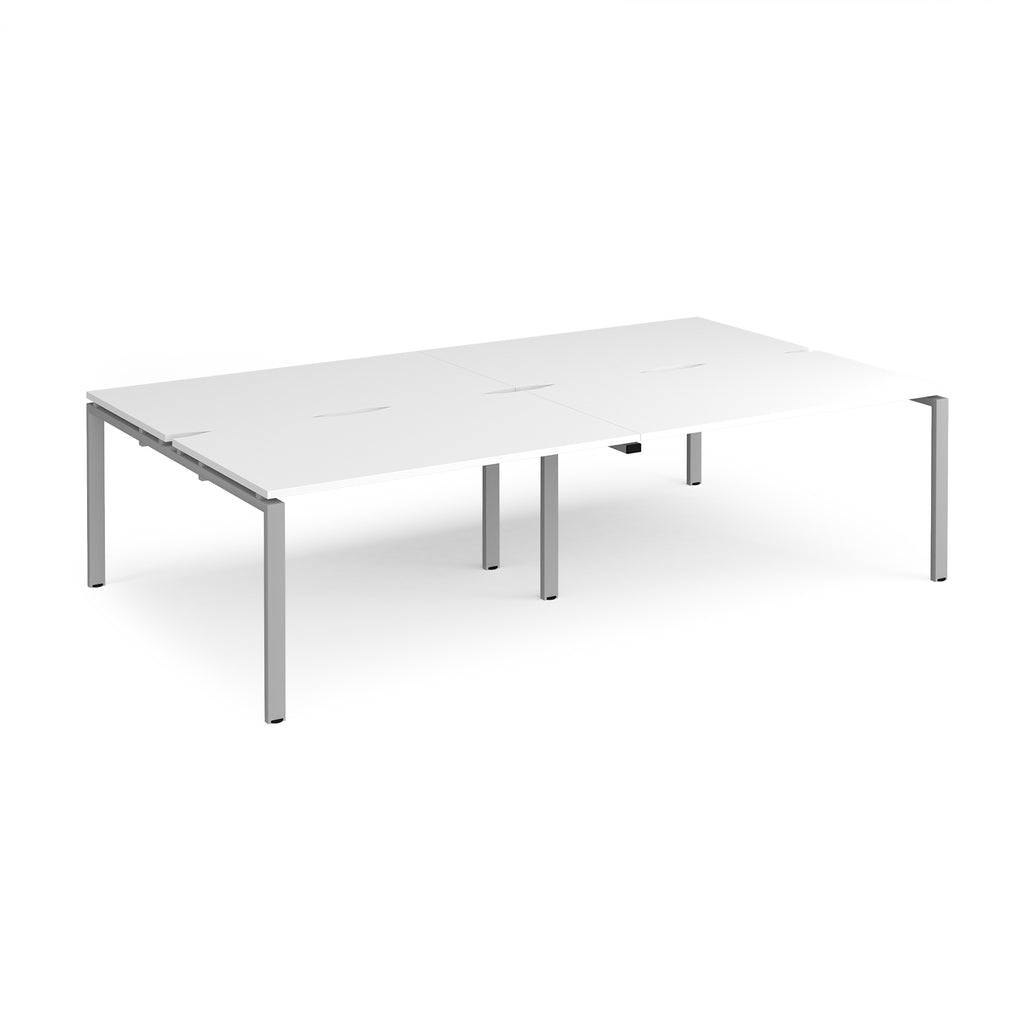 Four back-to-back desks with white tops and silver metal frame on a white background