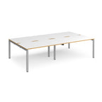 Four back-to-back desks with white tops with wooden edges and silver metal frame on a white background