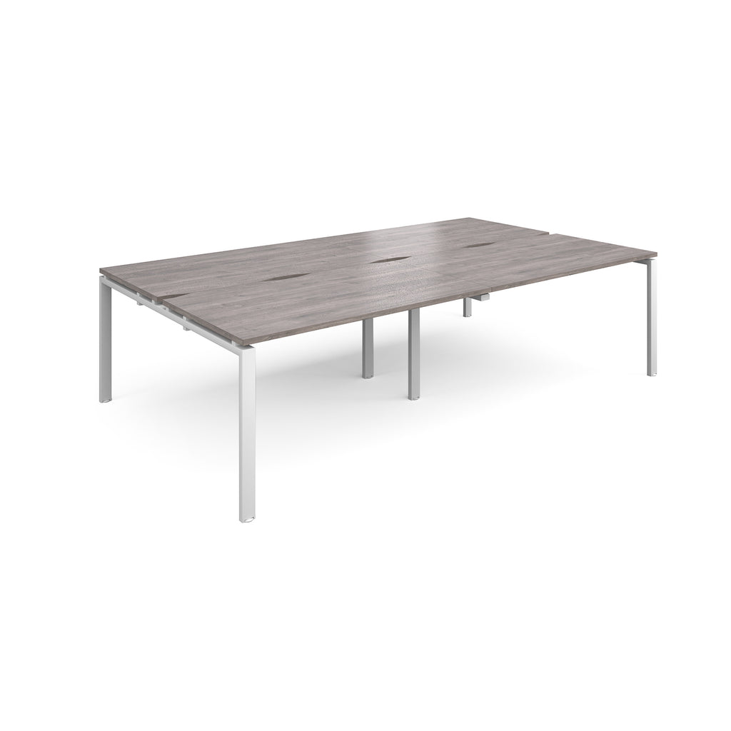 Four back-to-back desks with grey wood-effect tops and white metal frame on a white background