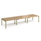 Long back-to-back desk with wood-effect top and green metal frame on a white background