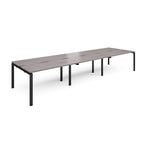 Long back-to-back desk with grey wood-effect top and black metal frame on a white background