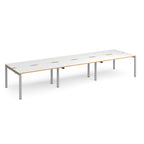Long back-to-back desk with white top with wooden edges and silver metal frame on a white background