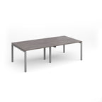 A rectangular office desk with a grey wood-grain tabletop and slim silver metal legs, shown on a clean white background.