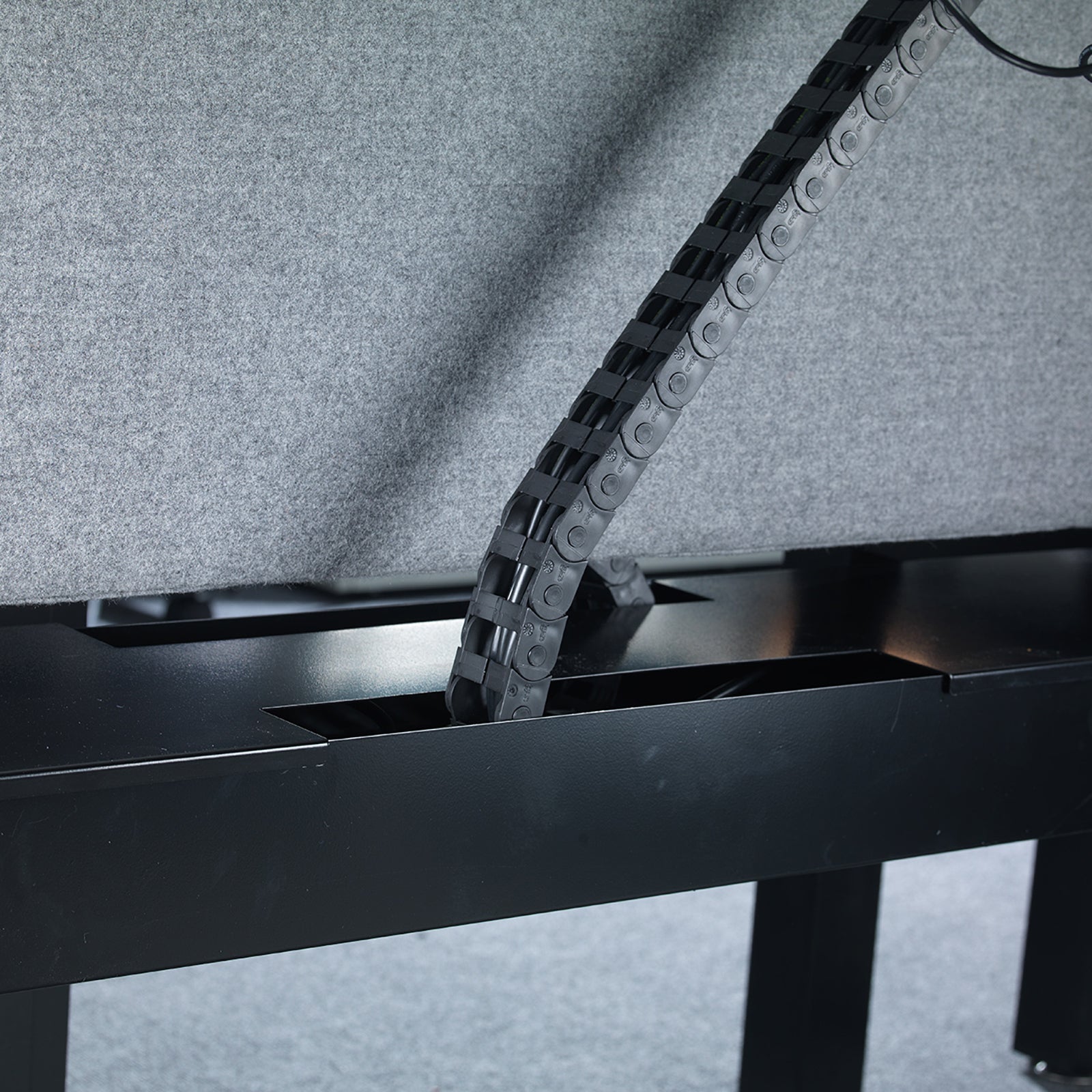 Metal chain running through a black metal frame on a grey background