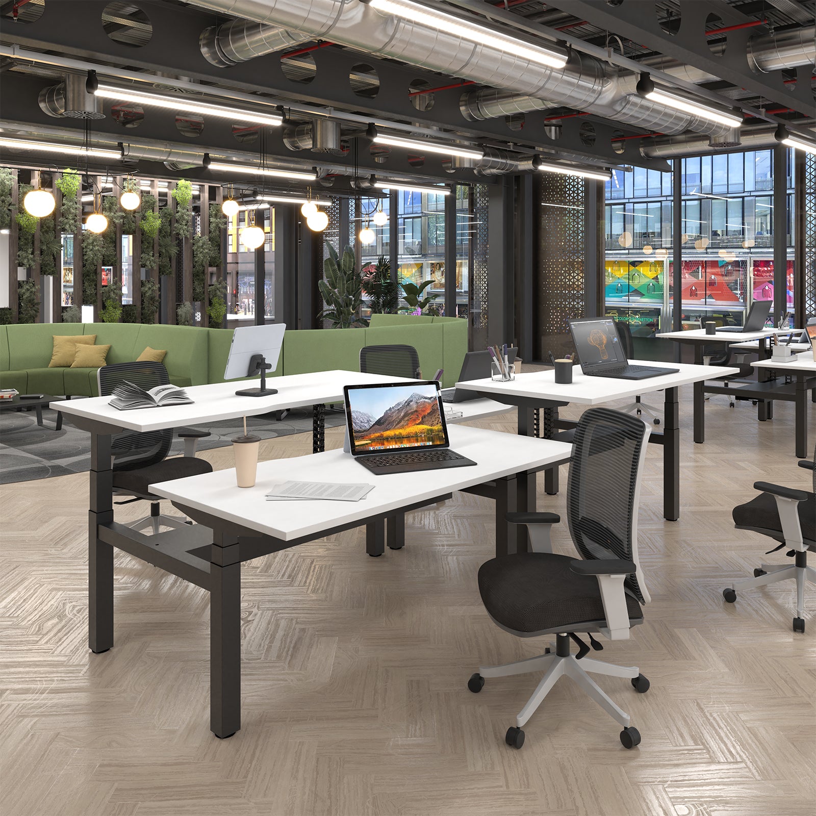 Modern open-plan office with multiple white desks, black metal frames, mesh office chairs, laptops, and a bright green sofa in the background.