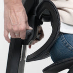 Person adjusting a black office chair with a white background