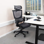 Black ergonomic chair in an office setting with a desk and window in the background.