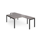 L-shaped back-to-back desks with grey wood-effect top and a black metal frame on a white background