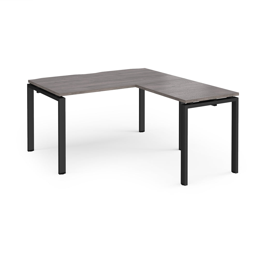 L-shaped desk with grey wood-effect top and black metal frame on a white background