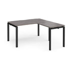 L-shaped desk with grey wood-effect top and black metal frame on a white background
