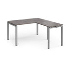 L-shaped desk with grey wood-effect top and silver metal frame on a white background