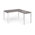 L-shaped desk with grey wood-effect top and white metal frame on a white background