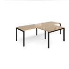 L-shaped back-to-back desks with wood-effect top and black metal legs on a white background
