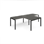 L-shaped back-to-back desks with grey top and black metal legs on a white background
