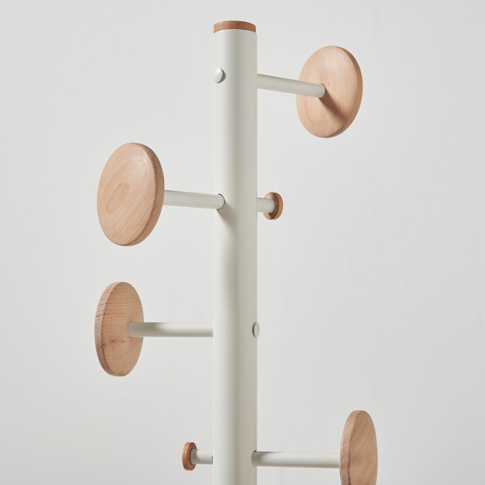 A modern coat rack with a matte white cylindrical pole and light wood grain circular hooks, shown against a plain light grey background.