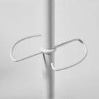 A close-up of a white metal coat rack with a central vertical pole and a curved horizontal hook at the centre, shown against a light grey background.