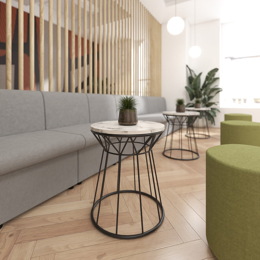 Modern interior with grey sofa, green stools, and marble-top side table.