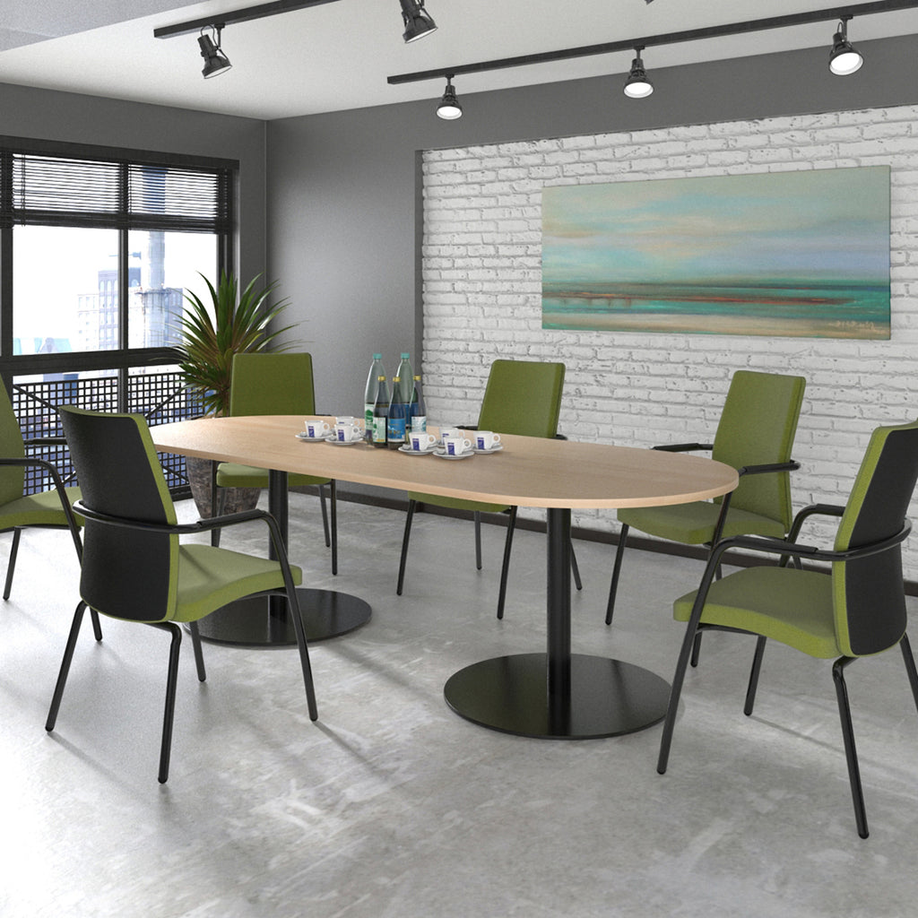 Modern conference room with a round table and green chairs against a white brick wall.