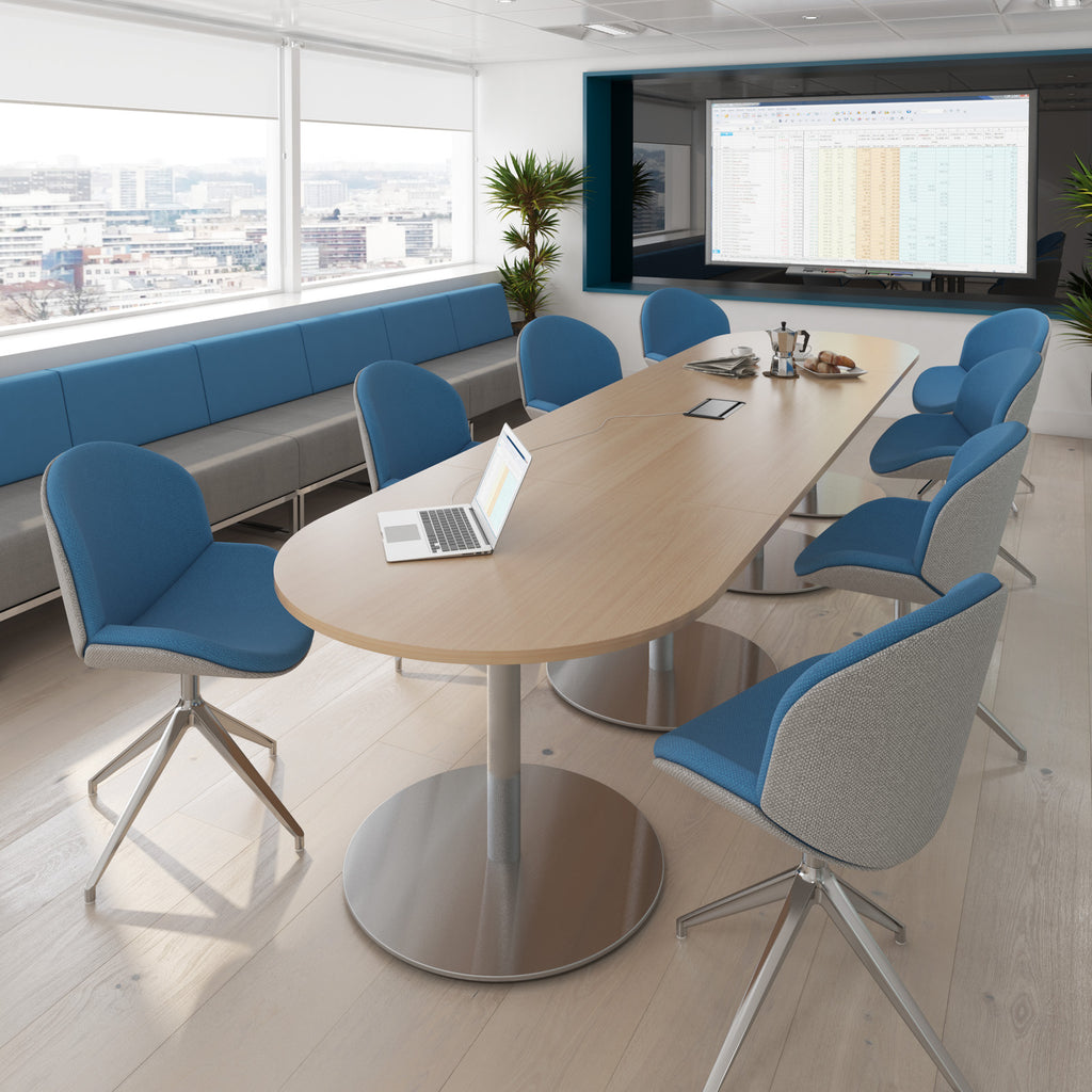 Modern conference room with a large oval table, blue chairs, and a screen displaying a presentation.