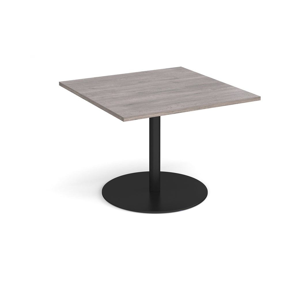 Square table with grey wood-effect top and black pedestal base on a white background