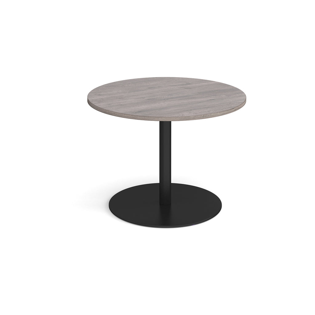 Round table with a light wooden top and black round base on a white background