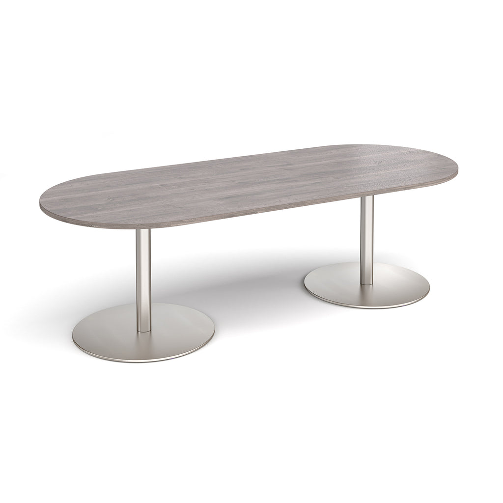 A modern oval conference table with a grey wood-grain top and dual silver metal pedestal bases, shown on a clean white background.