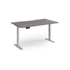 Height adjustable desk with grey wood-effect top and silver metal frame on a white background