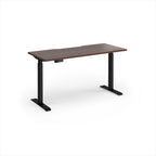 A modern height-adjustable desk with a dark brown wood-grain top and black metal legs, shown on a clean white background.