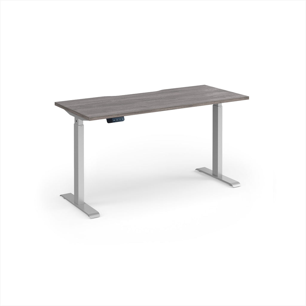 A modern height-adjustable desk with a grey wood-grain top and silver metal legs, shown on a clean white background.