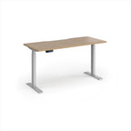 A modern height-adjustable desk with a light oak wood-grain top and silver metal legs, shown on a clean white background.