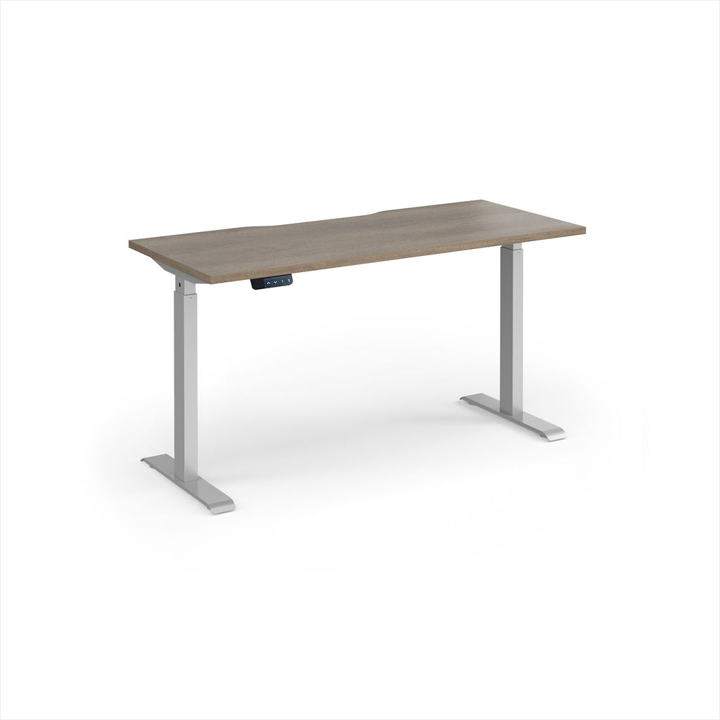 A modern height-adjustable desk with a grey wood-grain top and silver metal legs, shown on a clean white background.