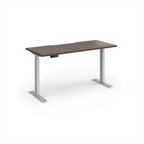 A modern height-adjustable desk with a dark brown wood-grain top and silver metal legs, shown on a clean white background.