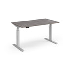 Sit-stand desk with grey wood-effect top and silver legs on a white background