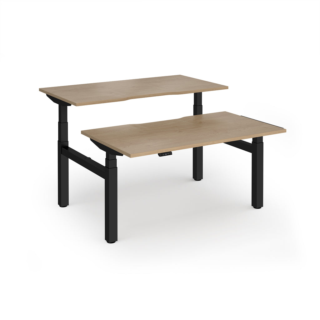 Two back-to-back height adjustable desks with shared black metal frame and wood-effect tops on a white background