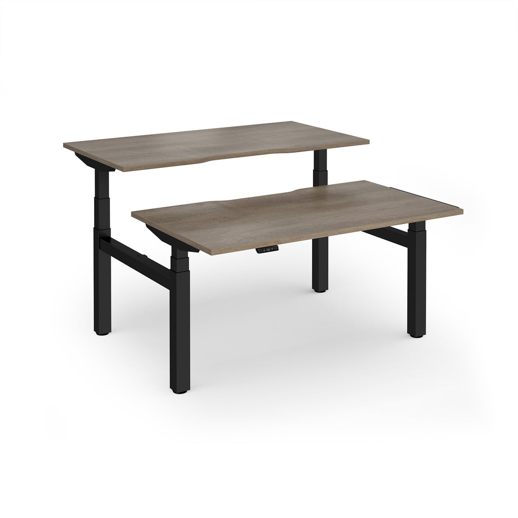 Two back-to-back height adjustable desks with shared black metal frame and wood-effect tops on a white background