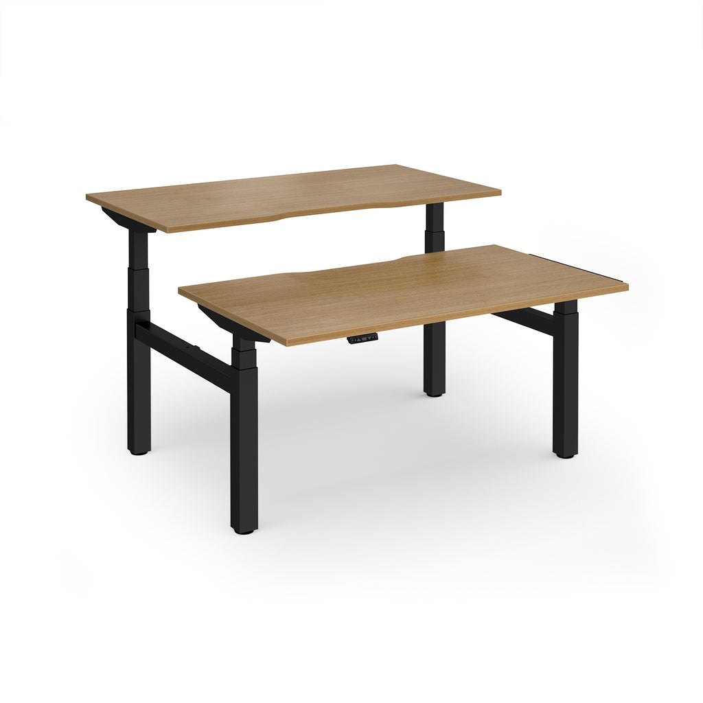 Two back-to-back height adjustable desks with shared black metal frame and wood-effect tops on a white background